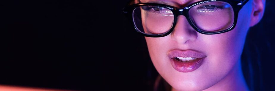 Imagem de mulher caucasiana usando óculos com filtro de luz azul em frente à tela