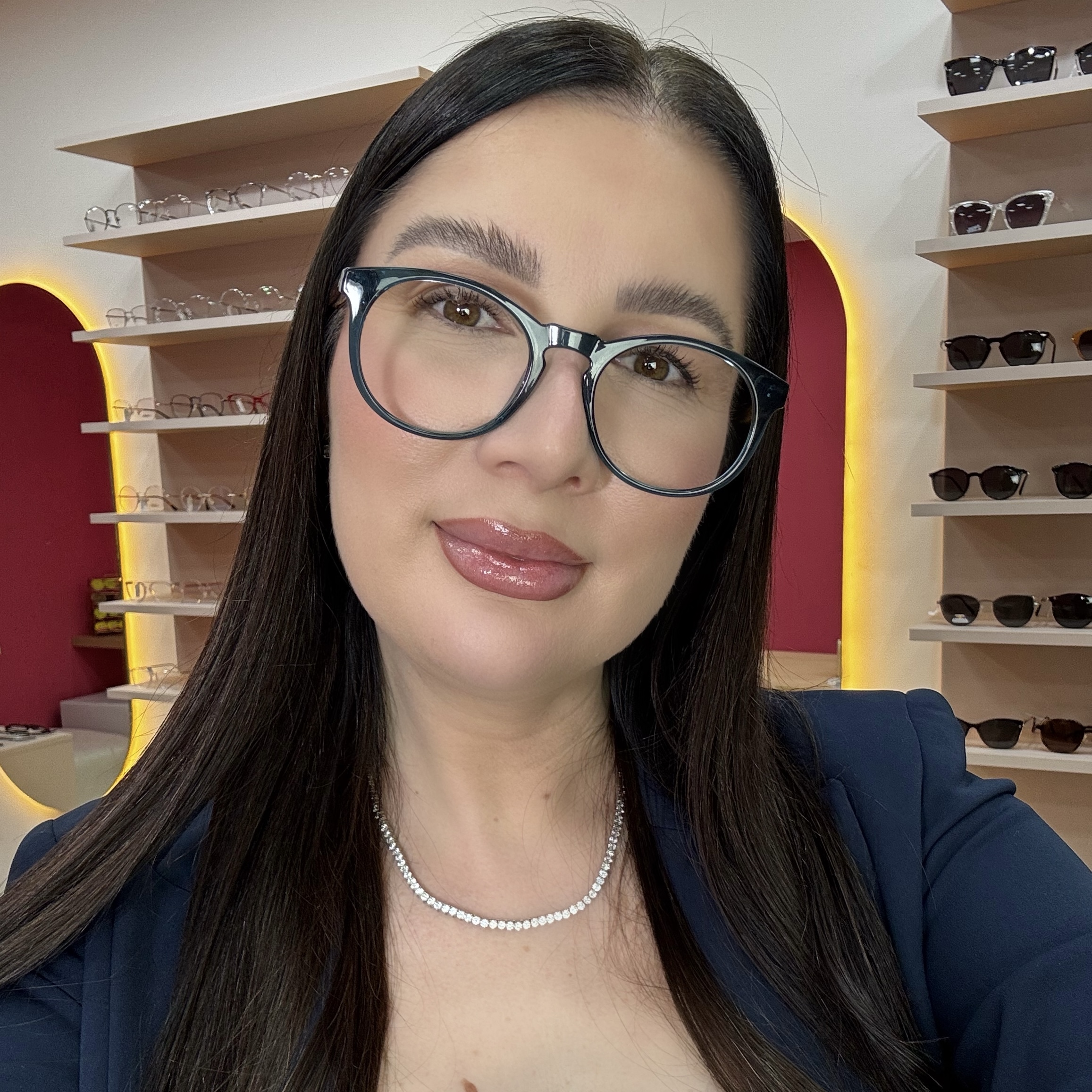 Ketlin Vasconcelos no showroom Kessy com óculos de grau azul — fundadora demonstrando como escolher armação para o formato do rosto
